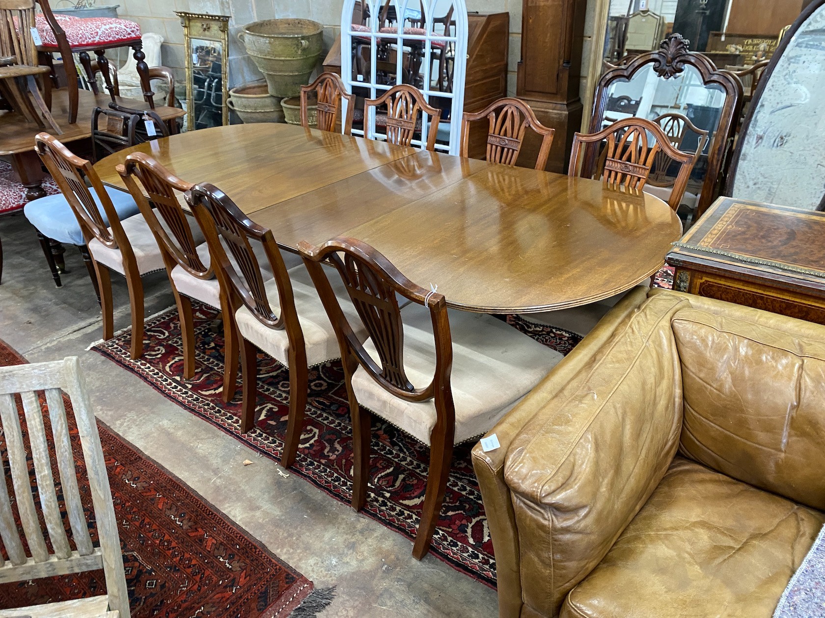 A William Tillman reproduction mahogany twin pedestal extending dining table, length 244cm extended, two spare leaves, depth 102cm, height 72cm and eight shield back dining chairs